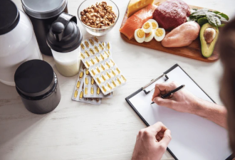 A top view of a desk with a notebook, pen, cup, nuts, and sliced oranges arranged neatly.
